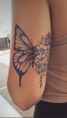 a woman's arm with a butterfly and flowers tattoo on the left side of her arm