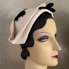 This Is An Amazing Sample Of The High Fashion Millinery Creations Of The Elegant 1950s'! This Asymmetrical Cap Is Made Of A Stiff Material Covered In A Beautiful Off White Colored Honeycomb Textured Fabric. The Cap Is Surrounded By Very Creative Folds As Shown In The Photos, Ending In A Point At One Side. The Top Of The Cap Is Trimmed With Black Curly Feathers, And The Front Has A Velour Covered Wire Made To Look Like A Twig, Ending Two Bulb Shapes Plus A Pearl At Each End. Throughout The 1950s, Ladies Wore Hats Daily As A Part Of Their Attire As Was A Pair Of Gloves. Post War 1940’s And 1950’s Saw Many Women Choosing Not To Wear Hats On A Regular Basis. To Preserve Its Market, The Mil Cream Cloche Hat For Evening, Fitted Retro Cream Hat, Retro Fitted Cream Hat, Retro Cream Hat, Vintage Cream Hat For Evening, Fitted Cream Hat For Vintage Events, Cream Brimmed Cloche Hat For Evening, Vintage Structured Crown Fascinator, Vintage Fascinator With Structured Crown