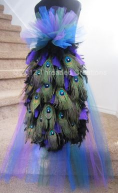 a dress made out of peacock feathers and tulle on the ground next to stairs