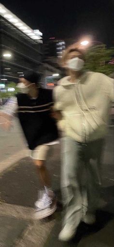 two people wearing face masks are walking down the street