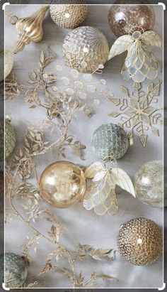 an assortment of christmas ornaments on a white tablecloth with gold and silver foiling