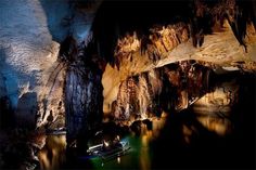 a boat is floating in the water near some cave walls and caves with lights on them