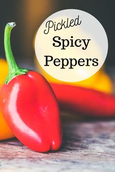 two red peppers sitting next to each other on top of a wooden table with the words pickled spicy peppers