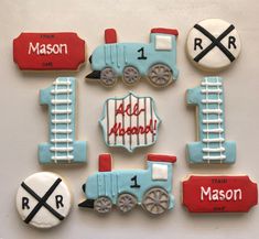 decorated cookies are arranged in the shape of trains and railroad tracks with names on them