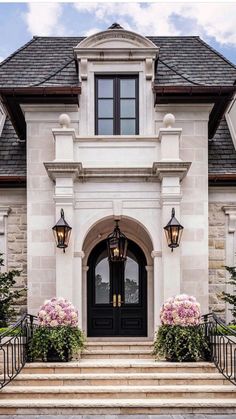 the front entrance to a large home with flowers on the steps and two lamps hanging from the roof