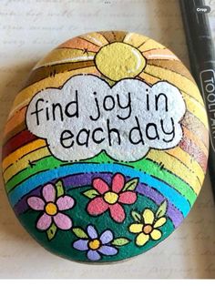 a painted rock with the words find joy in each day on it next to a marker