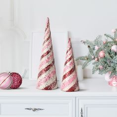 three pink and white christmas trees sitting on top of a dresser