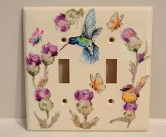 a light switch cover with flowers and a hummingbird painted on it's side