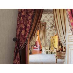 an open door leading to a bedroom with curtains on the walls and furniture in the room