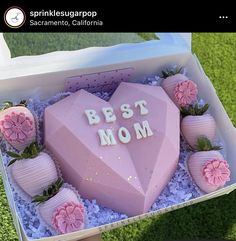 a pink heart shaped cake in a box with strawberries on the side that says best mom