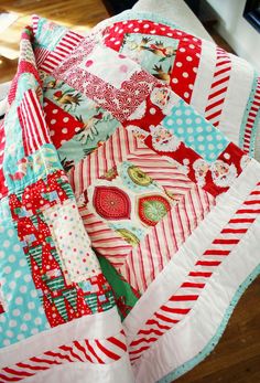 a close up of a quilt on a bed with red and white stripes, polka dots and hearts