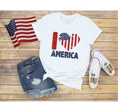 an american strong t - shirt with the american flag on it next to ripped jeans