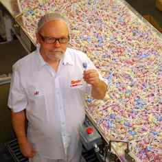 a man standing next to a conveyor belt filled with candy