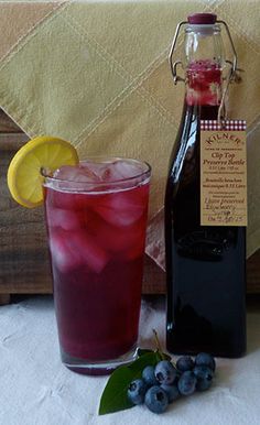 a bottle of wine next to a glass filled with blueberries