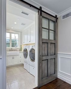 a washer and dryer in a white laundry room with an open barn door