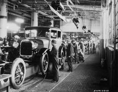 an old black and white photo of men working on cars in a car assembly line