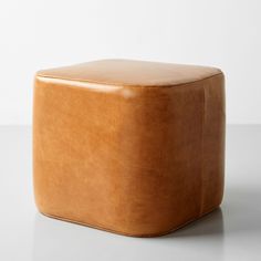 a brown leather stool sitting on top of a white table