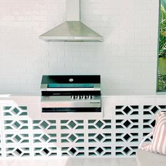 an outdoor kitchen with white tile and black grill