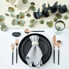 a place setting with black plates and silverware