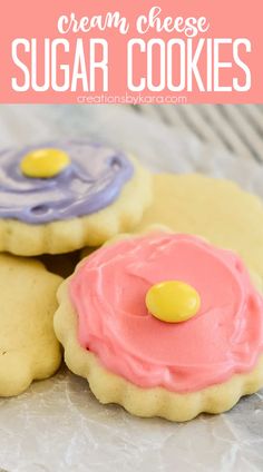 three sugar cookies with icing and candy on top, one is pink and the other is blue