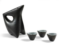 four cups and a black sculpture on a white background