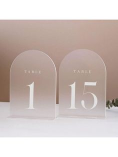 two clear acrylic table numbers are on display