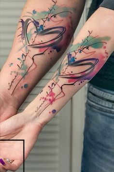 two people with tattoos on their arms holding each other's hands and one has the word