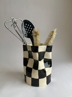 a black and white checkered cup with utensils in it