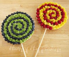 two lollipops with fruit on them sitting on top of a wooden table