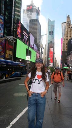 a woman standing in the middle of a busy city street with tall buildings behind her