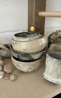 several bowls are stacked on top of each other with rocks and wood in the background