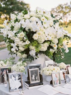 a table topped with pictures and flowers next to a vase filled with white hydrangeas