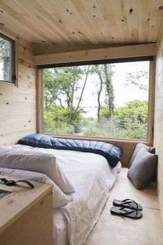 a bed sitting under a window next to a pair of flip flops