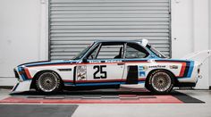 an old race car is parked in front of a garage door