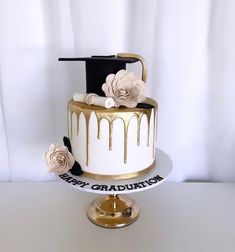 a white and gold graduation cake with flowers on top