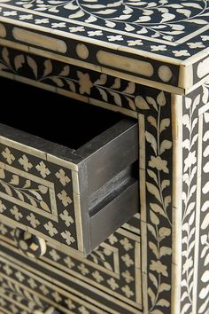 an ornate black and white box with drawers