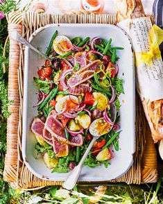 a white plate topped with salad next to bread