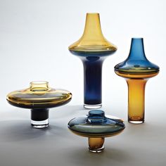 three different colored vases sitting next to each other on a white surface with no one around them