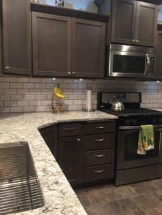 a kitchen with granite counter tops and dark wood cabinets, stainless steel appliances and sink