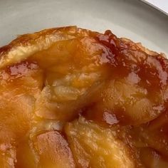 an upside down apple pie sitting on top of a white plate covered in caramel sauce