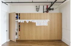 an empty room with wood floors and white curtains hanging from the ceiling, along with industrial pipes