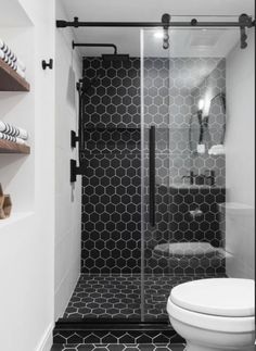 a white toilet sitting next to a black and white tiled shower stall in a bathroom