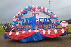 a group of people standing in front of a giant sign with balloons and decorations on it