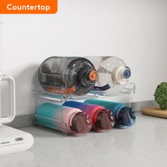 three different colored cups sitting on top of a counter next to a toaster and microwave