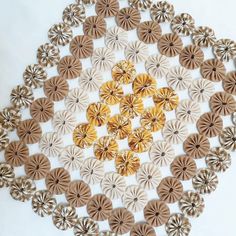 a circular design made out of brown and white paper flowers on a white tablecloth