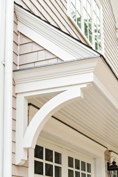 an arch on the side of a house that is white and has black trim around it