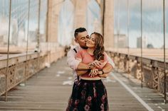 a man and woman kissing on the brooklyn bridge