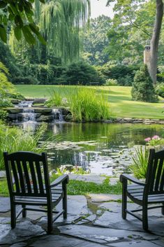 two wooden chairs sitting on top of a stone walkway next to a small pond in a park