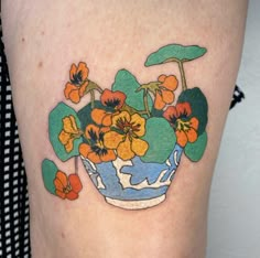 a tattoo with flowers in a vase on the thigh