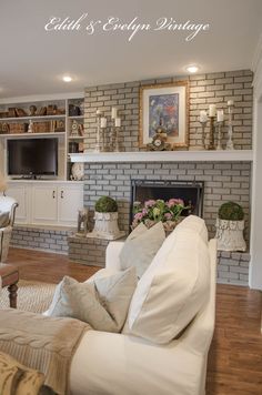 a living room filled with furniture and a fire place in front of a brick wall